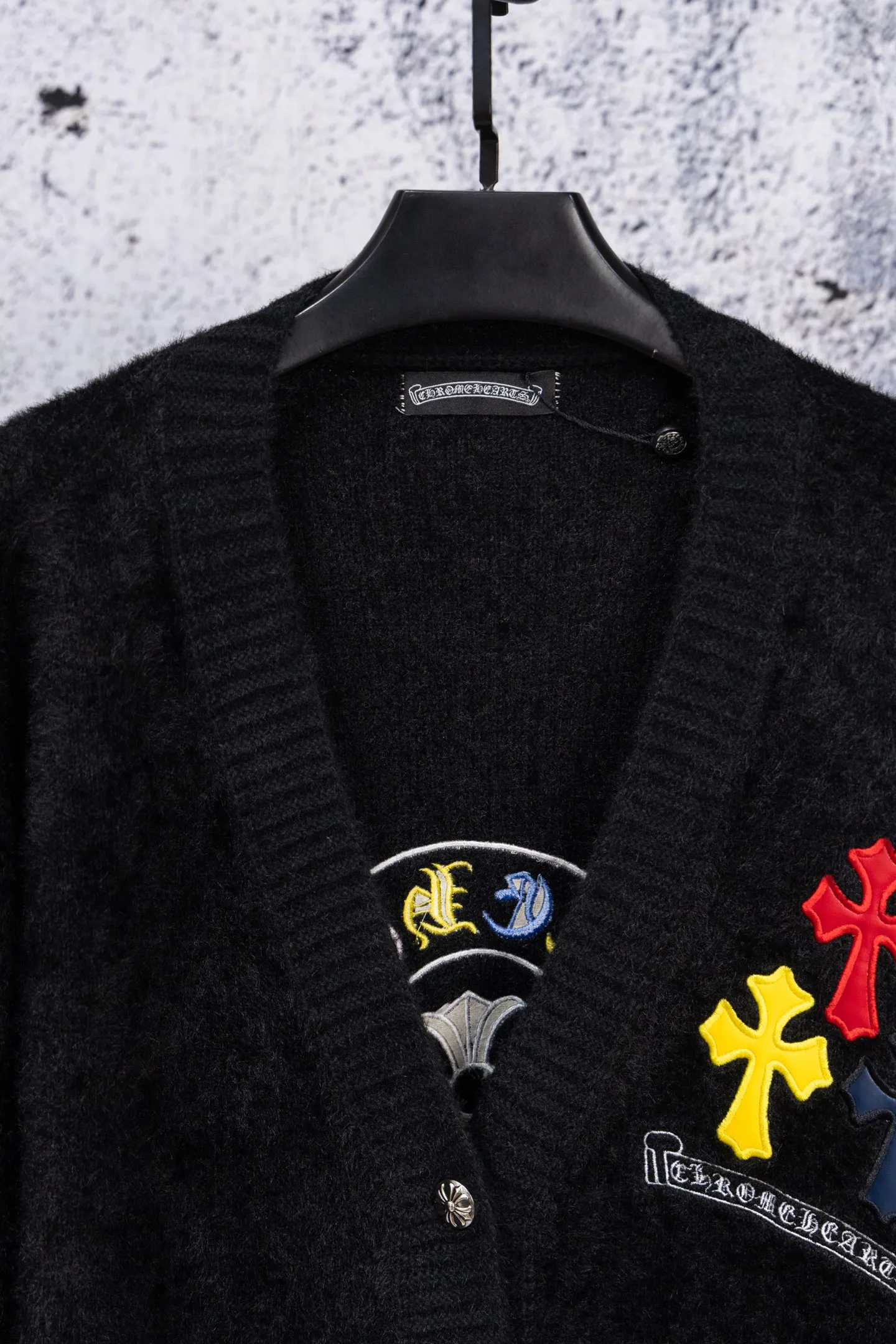 P300 Chrome Hearts CH Chrome Hearts 2026 new cross loose knitted V-neck cardigan Fabric: Made of plush textured knitted material, soft to the touch and with a lazy atmosphere; Decoration: Red, yellow, and black cross ornaments on the chest, paired with brand logo patches, which are iconic elements of street fashion brands (such as Chrome Hearts style), enhancing visual recognition; Version: Loose version + single-row metal button design, combining casual feeling and practicality. 2. Style and Adaptation Style: It combines dark street style and gentle knitted texture, which belongs to the tone of "sweet and cool mix"; Scenario: Can be worn with a T-shirt/suspender to create a daily street look, or can be layered with a shirt for light casual wear. Color: Black White Size: M L XL